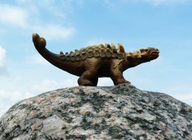 dinosaur on rock against the sky